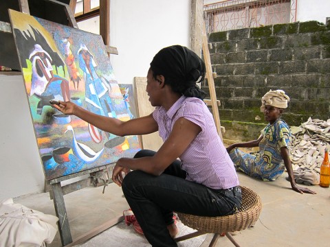 Rhode Makoumbou peignant dans son atelier à Mansimou. À droite : sa mère, Élisabeth Makoumbou