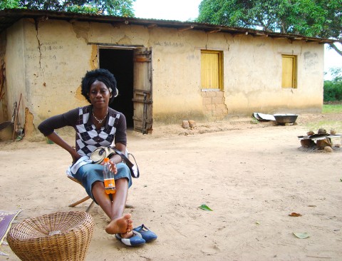 Rhode Makoumbou assise devant la maison où elle s'était réfugiée avec sa famille durant la guerre civile de 1997